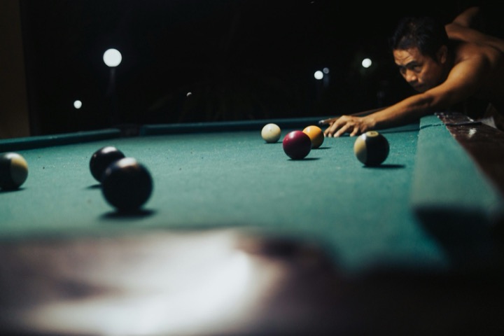 Long-exposure photograph of colourful billiard balls streaking across a dark table