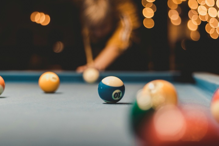 Close-up of a blue ten ball on a pool table with warm string lights blurred behind